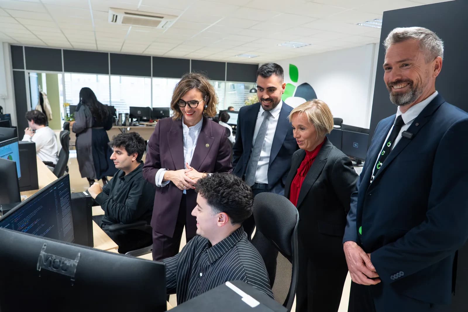Elixabete Etxanobe, Ainara Basurko y John Pollock junto a un compañero de RK Solutions frente a su ordenador